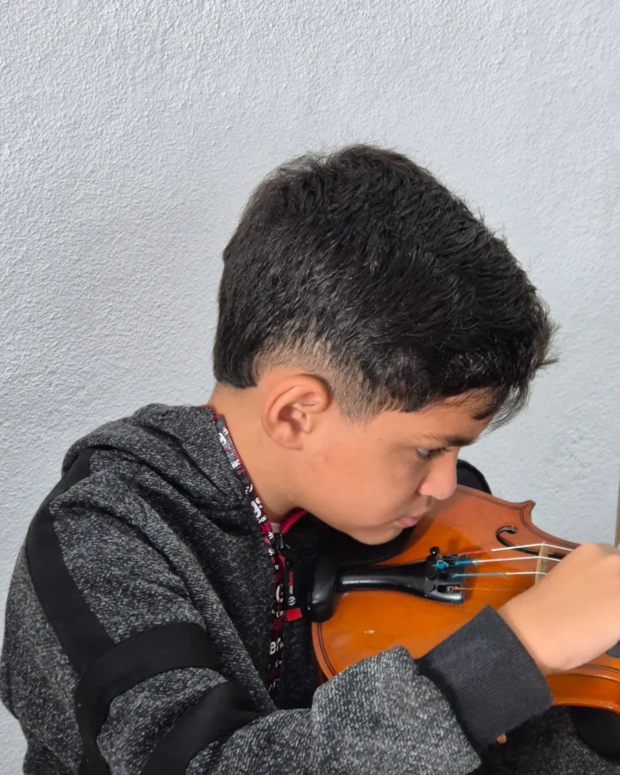 Menino de perfil tocando violino