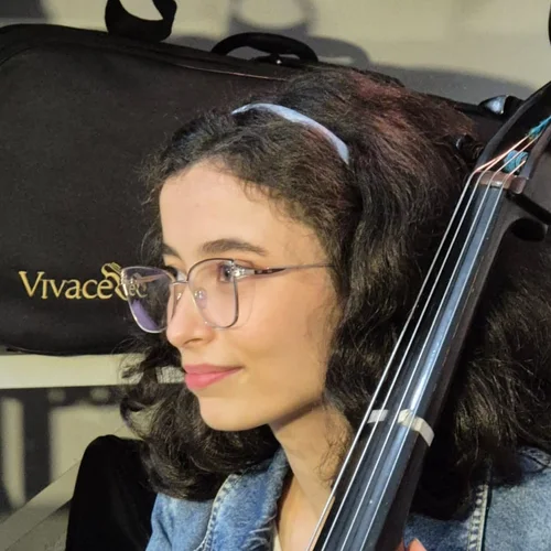 Ana Maria, professora de violoncelo, ao lado do instrumento