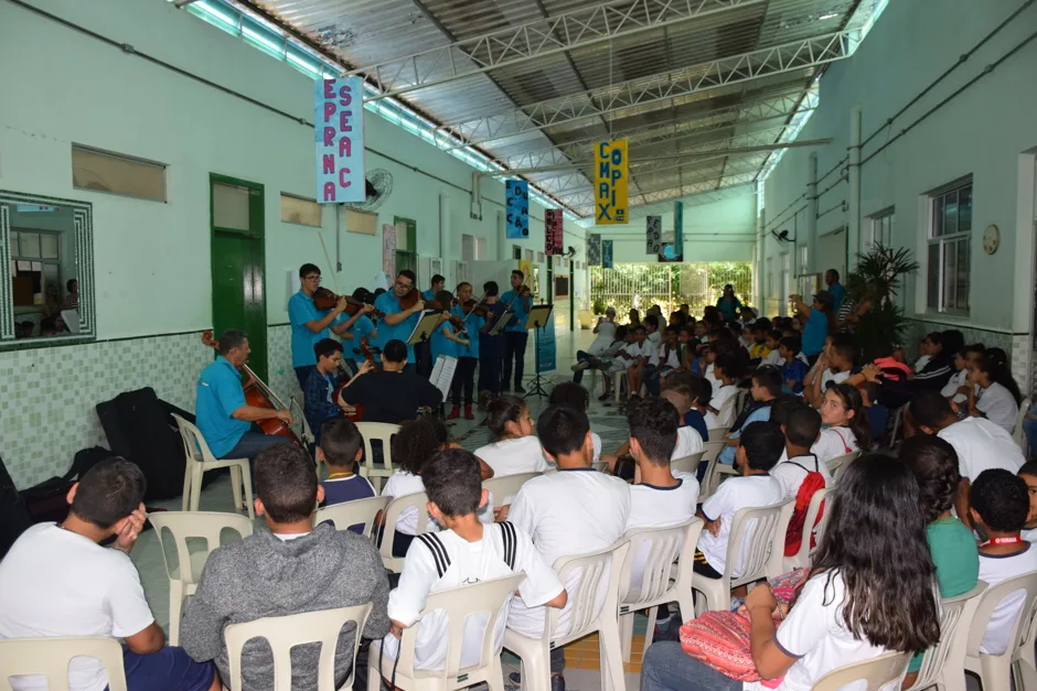 Concerto didático da Orquestra Jovem para estudantes em pátio coberto de escola da Fundhas